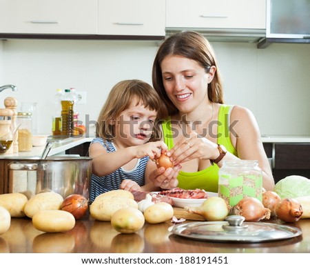 Happy mother with daughter cooking with groats at home