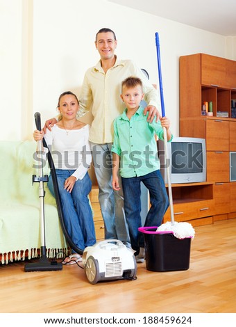 Portrait of happy family of three with  cleaning equipment in home