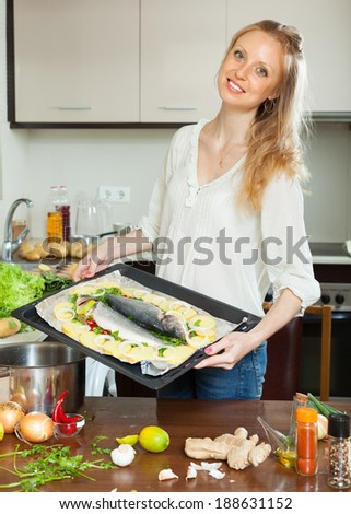 Ordinary woman cooking fish with potato in sheet pan at home kitchen