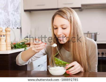 Happy woman eating cottage cheese at table