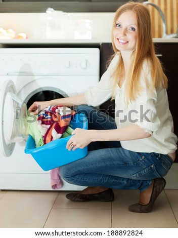 Long-haired blonde woman using washing machine at home