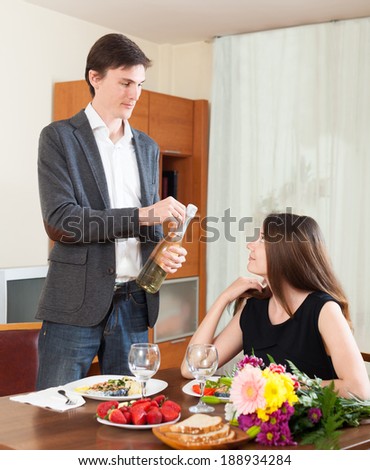 Man opens champagne for a romantic dinner at home