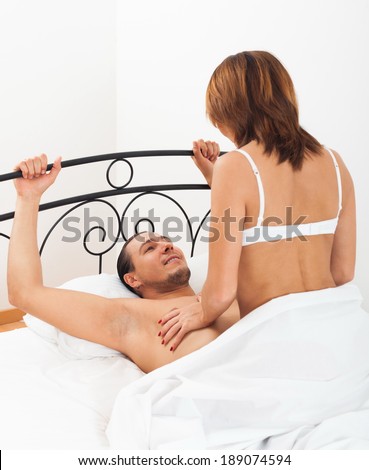 Adult man and woman having sex on bed in home interior