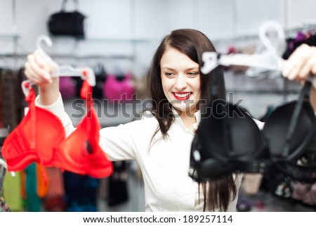 Smiling ordinary girl choosing bra at fashion shop