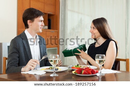 Woman  giving gift  to man at table during romantic dinner
