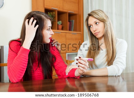 Blonde woman consoling the worried girl with pregnancy test at home