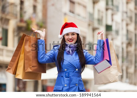 Smiling young girl with shopping bags at street during the Christmas sales