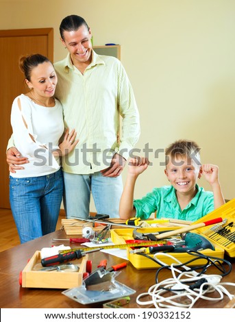 Happy teen making something with working tools, parents are watching at home