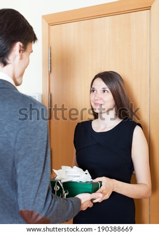 beautiful girl presents gift to man in the door