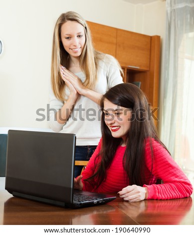 Two young women  with laptop at table in home