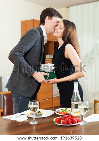 Girl giving present to man at table