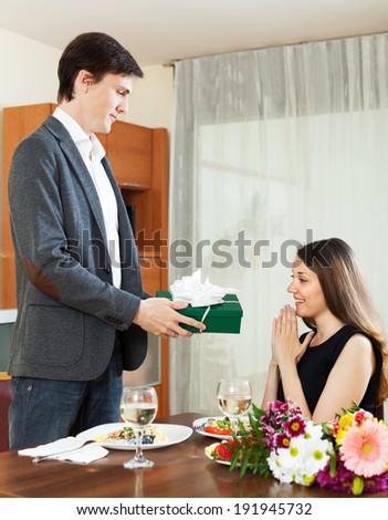 Man giving present to woman during romantic dinner with champagne