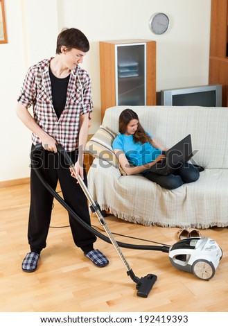 Clean up man, while wife lying with notebook on the sofa