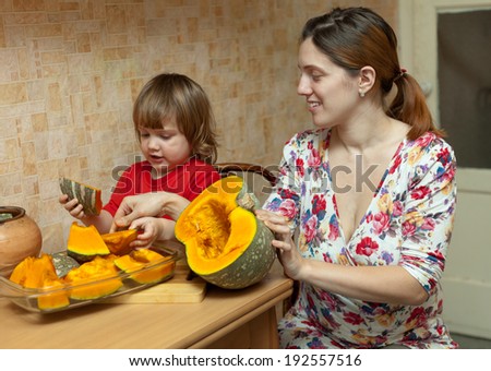 mother with girl cooks pumpkin in kitchen at her home