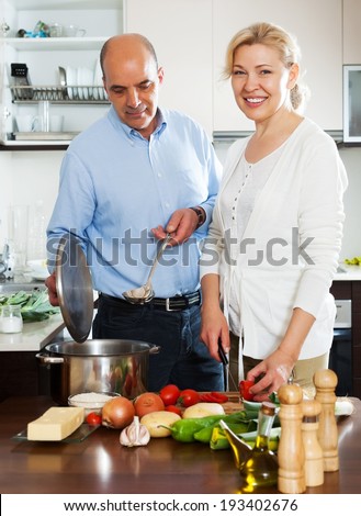 Elderly couple cooking vegetarian soup at home kitchen