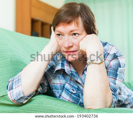 Portrait of sad senior woman having tough time and laying on couch