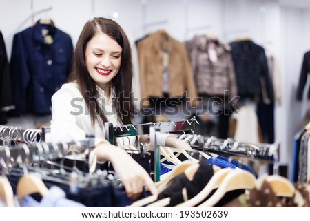Brunette long-haired girl choosing  wear at clothing store