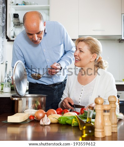 Elderly vegetarian family cooking food together and smiling