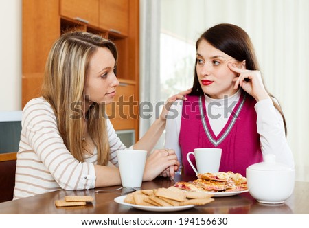 woman consoling the depressed woman at table in home