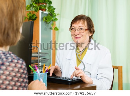 Smiling elderly doctor advises female patient in office
