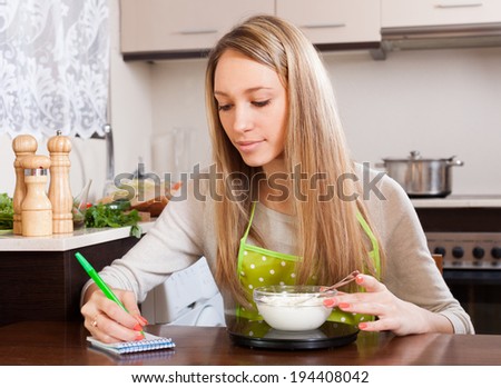 Woman weighing curd cheese on kitchen scales