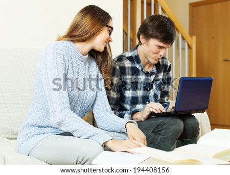Happy young couple with laptop preparing for exam