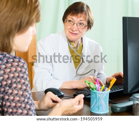 An elderly doctor advises a woman in a doctor\'s office