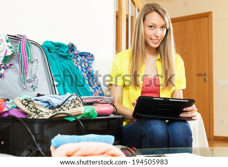 Smiling young woman browsing places to visit with tablet before going on leave