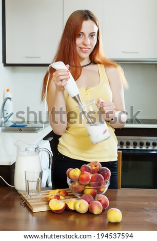 woman cooking milk beverages with electric blender from peaches