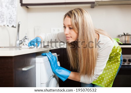 Blonde woman cleaning  furniture in kitchen at home