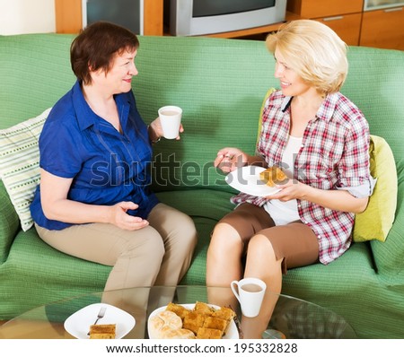 Two women colleagues in years drinking coffe and talking during coffee break