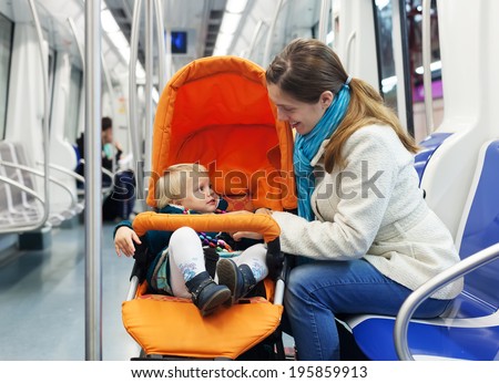 Smiling woman with baby in stroller at subway train