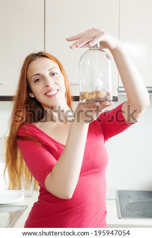 Girl in red washing glass bottle with egg shell in home kitchen