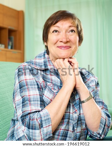 elderly woman in casual clothes sitting on couch  and smiling