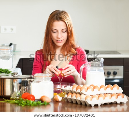 girl in red cooking omelet with eggs in home kitchen