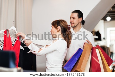 Woman and man with shopping bags choosing dress at boutique