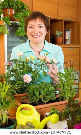 Happy mature gardener with flowers smiling at home interior