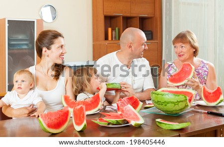Happy three generations family eating watermelon  over  table at home interior