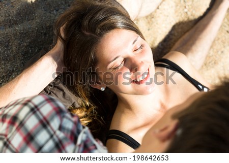 Smiling  woman with closed eyes lying on the lap of a  man on the beach
