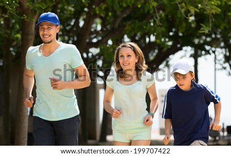 Happy family of three jogging in summer morning