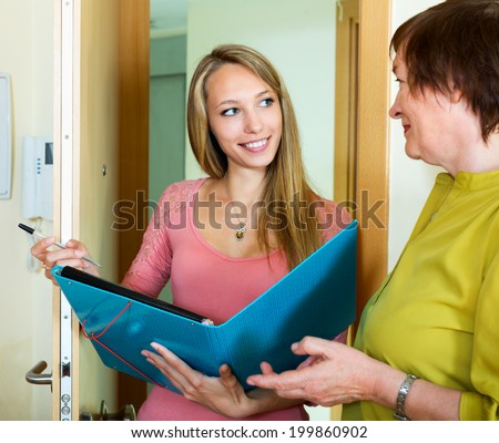 Mature  woman answers the questions of smiling employee  in door