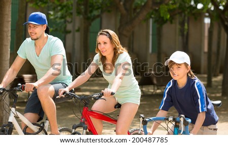 Active family riding bikes in the park summer day