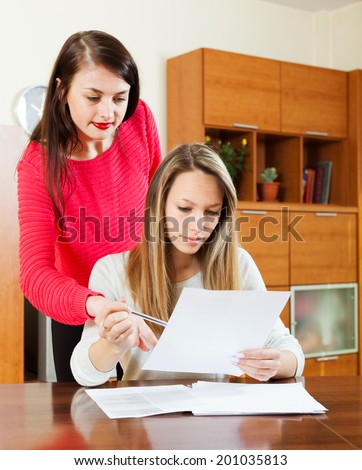 serious women with financial documents at table in home or office interior