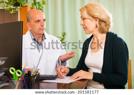 Male doctor talking with mature patient in clinic office