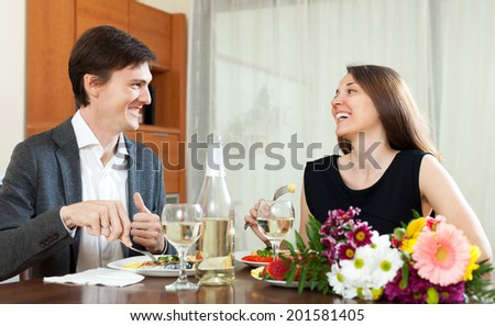 Young man and smiling woman having romantic dinner in home