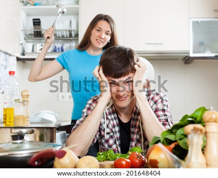 Family quarrel. Unhappy young man with angry wife at home