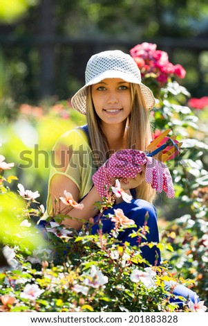Happy young girl  in uniform at yard gardening with roses