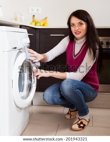 Smiling brunette woman cleaning washing machine at home
