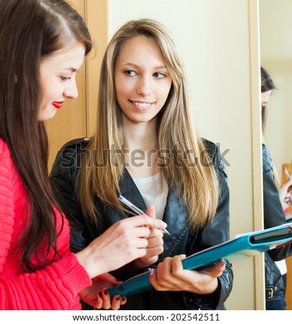 woman answer questions of smiling woman with papers at door