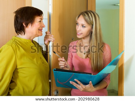 Woman answers the questions of young employee  in door at home